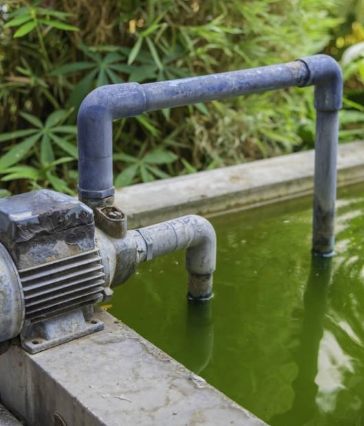 image of Water pump, pumping waste water from green rotten ponds.